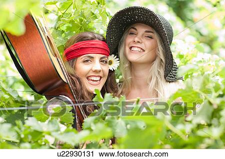 Stock Image - Women holding guitar? in tall plant. Fotosearch