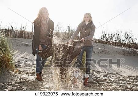 Women shaking out beach blanket View Large Photo Image Stock Photography - Women shaking out beach blanket. Fotosearch