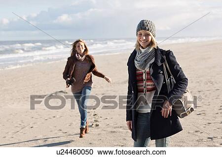 Stock Image - Women walking on beach. Fotosearch