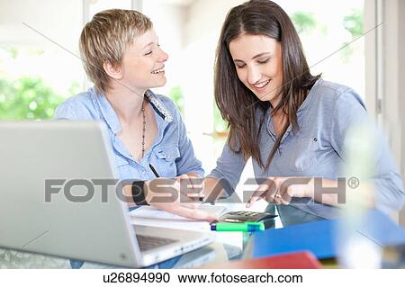 Women working together at desk View Large Photo Image Stock Image - Women working together at desk. Fotosearch