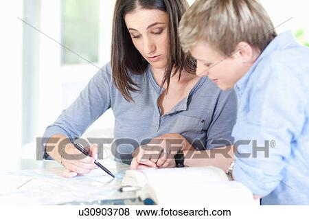 Women working together at desk View Large Photo Image Stock Photo - Women working together at desk. Fotosearch
