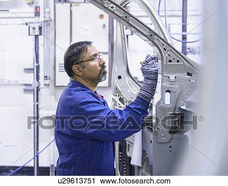 Stock Image - Worker applying sealant in car factory. Fotosearch