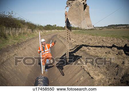 Stock Image - Worker directing digger in surface mine. Fotosearch