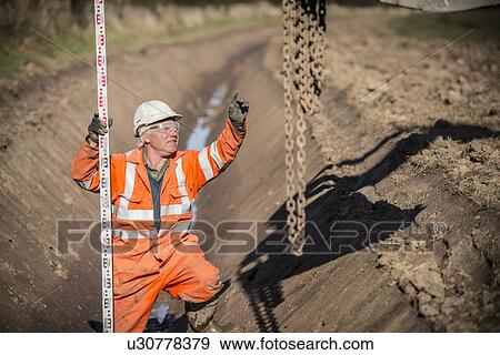 Worker directing digger in surface mine View Large Photo Image Stock Photo - Worker directing digger in surface mine. Fotosearch