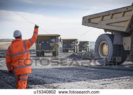 Worker directing trucks at surface mine View Large Photo Image Stock Image - Worker directing trucks at surface mine. Fotosearch