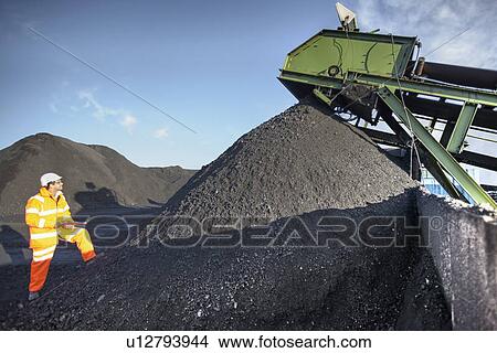 Worker examining pile of coal at mine View Large Photo Image Picture - Worker examining pile of coal at mine. Fotosearch