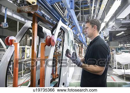 Stock Photograph - Worker fitting parts in car factory. Fotosearch