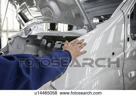 Stock Photo - Worker inspecting car in factory. Fotosearch