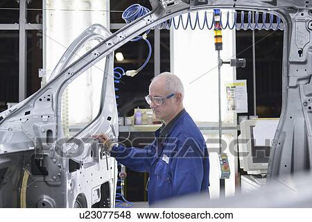 Stock Photo - Worker inspecting car in factory. Fotosearch