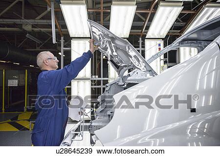 Stock Photo - Worker inspecting car in factory. Fotosearch