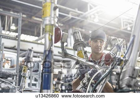 Worker inspecting parts in car factory View Large Photo Image Stock Image - Worker inspecting parts in car factory. Fotosearch