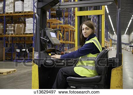Stock Photo - Worker operating forklift in warehouse. Fotosearch