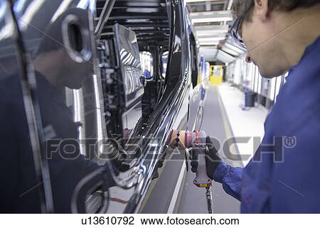 Stock Image - Worker polishing car in factory. Fotosearch