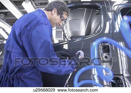 Stock Photo - Worker polishing car in factory. Fotosearch
