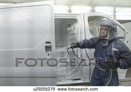 Stock Photo - Worker spray painting in car factory. Fotosearch