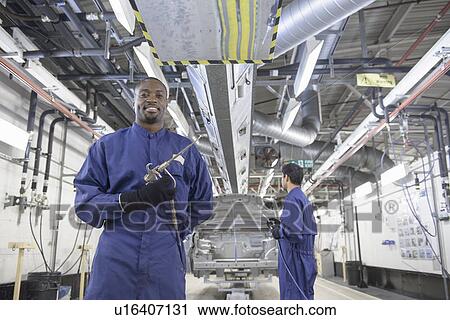 Worker standing in car factory View Large Photo Image Stock Image - Worker standing in car factory. Fotosearch