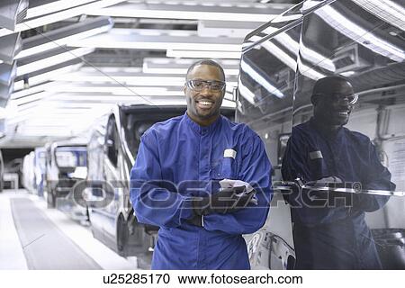 Worker standing in car factory View Large Photo Image Stock Image - Worker standing in car factory. Fotosearch