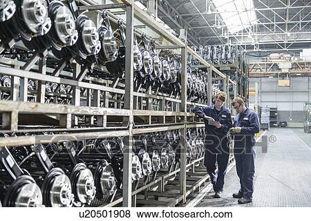 Stock Photo - Workers inspecting axles in car factory. Fotosearch