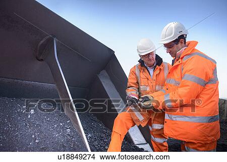 Picture - Workers inspecting coal at surface mine. Fotosearch