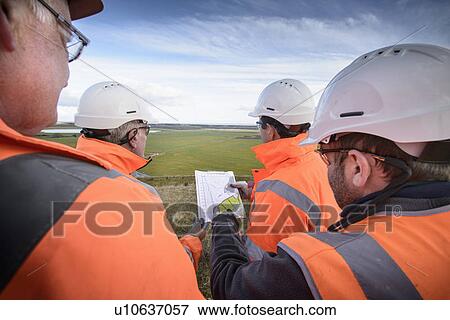 Stock Photo - Workers reading blueprints in field. Fotosearch