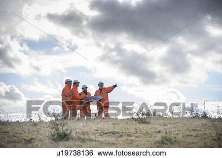 Workers reading blueprints in field View Large Photo Image Stock Photograph - Workers reading blueprints in field. Fotosearch