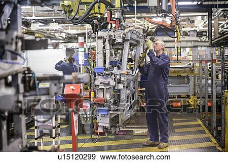 Stock Photo - Workers with machinery in car factory. Fotosearch