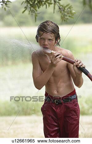 Stock Photography - Boy (10-11) drinking from water hose in summer. Fotosearch