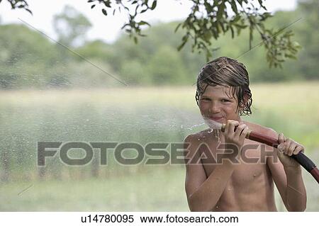 Stock Photography - Boy (10-11) drinking from water hose in summer. Fotosearch
