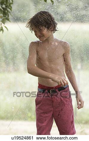 Boy (10-11) playing with splashing water View Large Photo Image Stock Image - Boy (10-11) playing with splashing water. Fotosearch