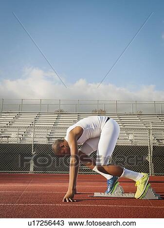 Stock Image - Boy (12-13) preparing for running on starting line. Fotosearch