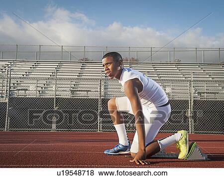 Stock Photo - Boy (12-13) preparing for running on starting line. Fotosearch