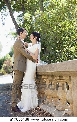 Stock Photo - Bride and groom embracing in park. Fotosearch