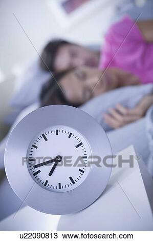 Stock Image - Close up of alarm clock on bedside table. Fotosearch