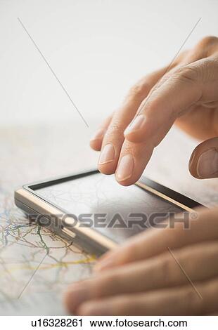 Stock Image - Close-up of hand using gps system. Fotosearch