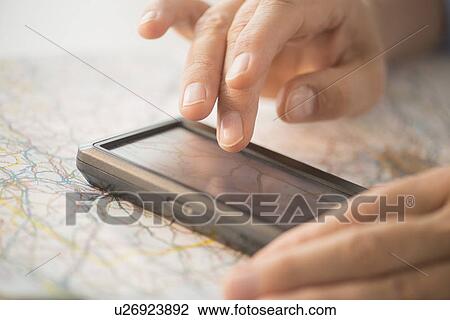 Stock Image - Close-up of hand using gps system. Fotosearch