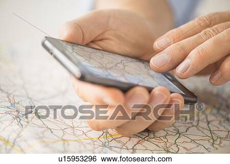 Close-up of hand using smartphone over map View Large Photo Image Stock Photograph - Close-up of hand using smartphone over map. Fotosearch