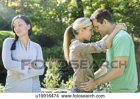 Couple and unhappy woman in forest View Large Photo Image Picture - Couple and unhappy woman in forest. Fotosearch