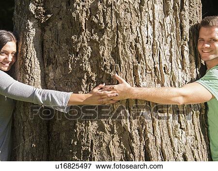 Stock Photo - Couple embracing large tree. Fotosearch