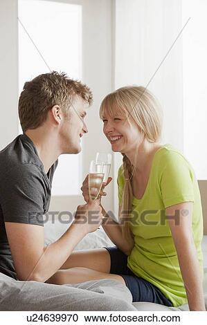 Stock Image - Couple enjoying champagne in bed. Fotosearch