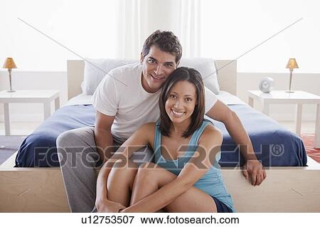 Stock Photo - Couple in embrace sitting in bedroom. Fotosearch