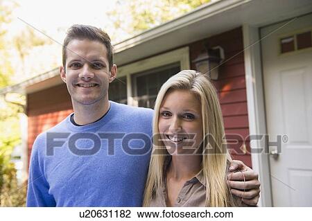 Stock Image - Couple in front of cottage. Fotosearch