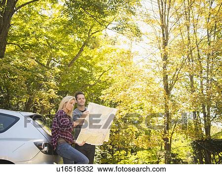 Couple leaning against car and reading map View Large Photo Image Stock Image - Couple leaning against car and reading map. Fotosearch