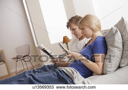 Stock Image - Couple sitting in bed reading. Fotosearch
