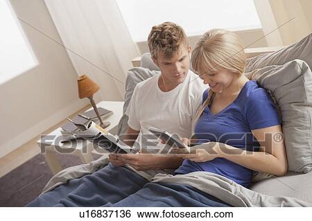 Stock Photograph - Couple sitting in bed reading. Fotosearch