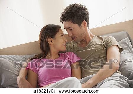 Stock Image - Couple sitting in bed with face to face. Fotosearch