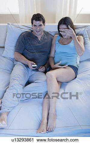 Couple sitting on bed and watching tv View Large Photo Image Stock Image - Couple sitting on bed and watching tv. Fotosearch