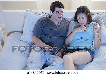 Couple sitting on bed watching television View Large Photo Image Stock Image - Couple sitting on bed watching television. Fotosearch