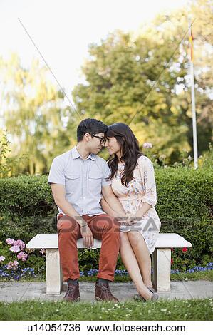 Stock Photograph - Couple sitting on bench in park. Fotosearch