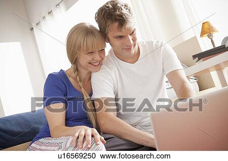 Stock Image - Couple sitting on floor using laptop. Fotosearch