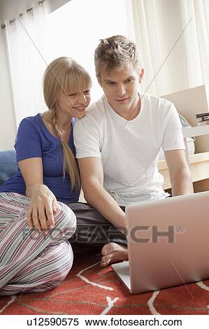Stock Photography - Couple sitting on floor using laptop. Fotosearch